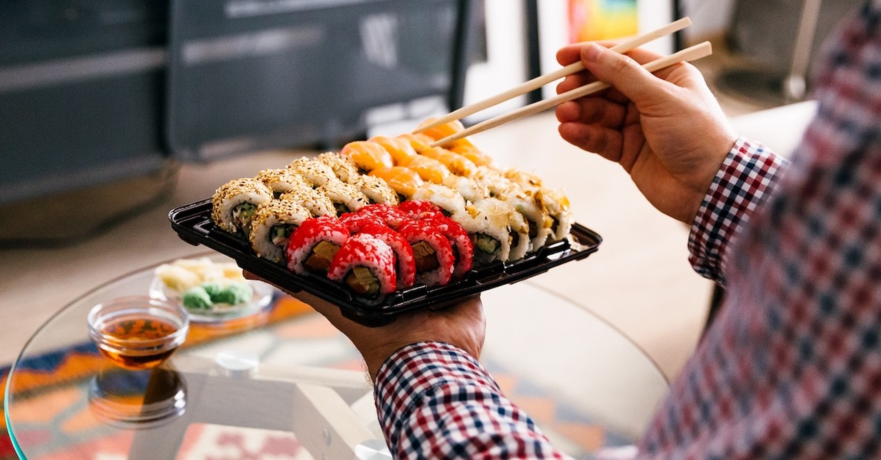 Man eating takeout sushi at home watching TV dinner