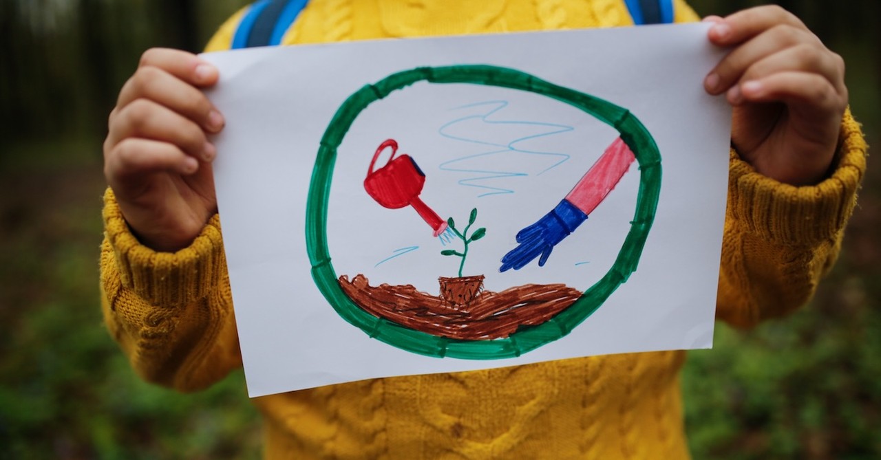 Earth Day art child holding drawing on nature hike