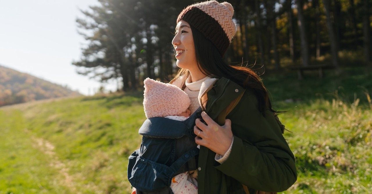 Mom on hike babywearing daughter holding baby