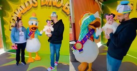 Baby Clings to Donald Duck's Hand in Precious Moment