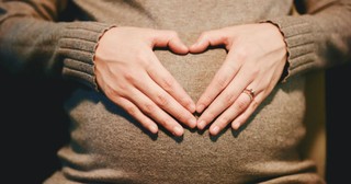 Pregnant mom making a heart sign over belly