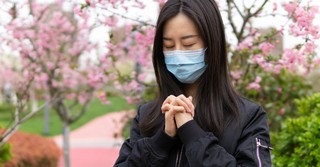 Woman wearing a surgical mask and praying