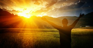 Man raising his arms toward the sunrise