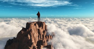 man standing on rocky peak above clouds