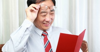Man lifting his glasses to read