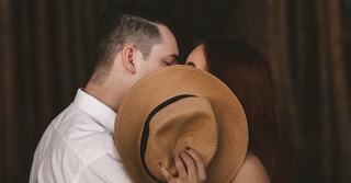Couple kissing behind a hat