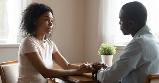 woman and man couple holding hands sitting talking looking serious, how to respond to spouse doubts