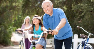 grandparents with grandchild helping her ride a bike