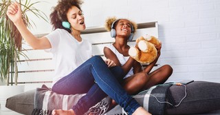 joyful mom and daughter singing praise songs with headphones on