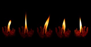 five candles in a row burning in the dark
