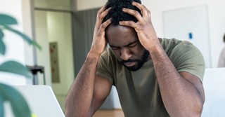 stressed at work man holding head in hands overcome anxiety