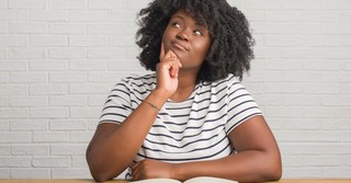 woman looking up and questioning what is in book