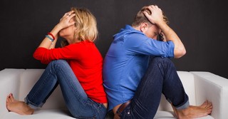couple sitting back to back on couch looking upset