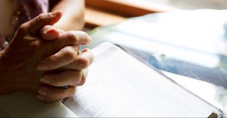 Folded hands over the Bible