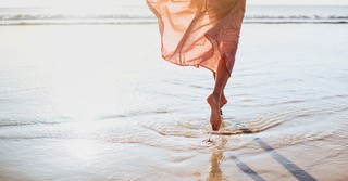 woman running along shore in bare feet