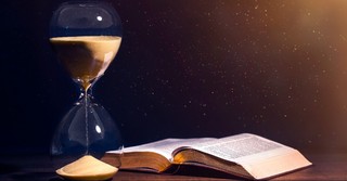 Bible opened with an hour glass