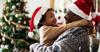grandchild and grandparent hugging at christmas with santa hats