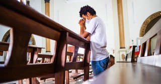 Man kneeling at a pew praying