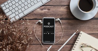 Podcast on a phone, coffee, and a keyboard