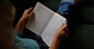 a little girl reading a Bible