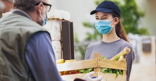 Young woman delivering groceries to an elderly man