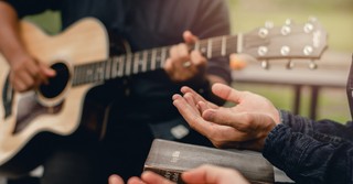 a person playing a guitar and a person holding a Bible