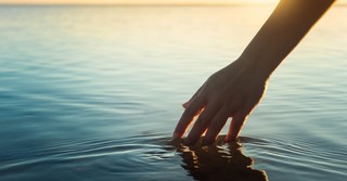 a person's hand in a body of water