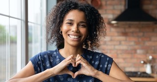 Woman smiling with her hands in the form of the heart