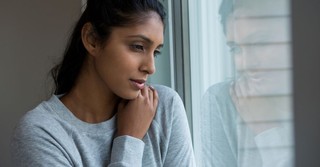 woman looking out window, lonely and thinking