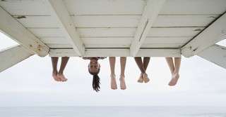 feet hanging down above water with one little girl leaning down smiling