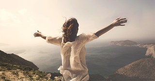 Woman with arms raised in praise on a mountaintop