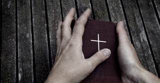Hands holding a small Bible