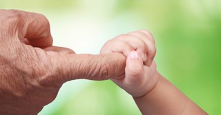 Baby grasping a senior's finger