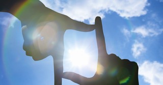 Fingers framing the sun