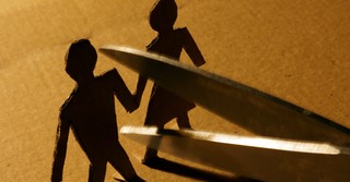 Scissors cutting apart a cardboard couple
