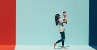 Mom holding baby in front of a colorful mural