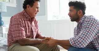 adult child man holding hands of senior father dementia alzheimers