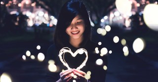 Young woman holding string lights shaped like a heart