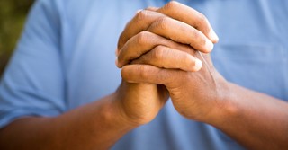 Close-up of a man's hands folded in prayer