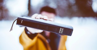 Close up of a man holding out a Bible