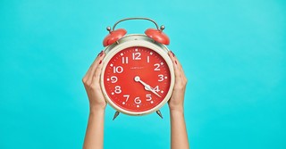 Woman holding up an old fashioned alarm clock