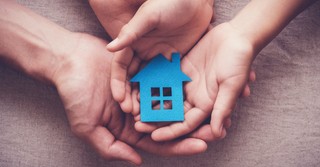 hands in pile holding paper house symbol