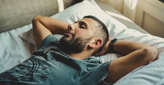 A man asleep with his hands behind his head