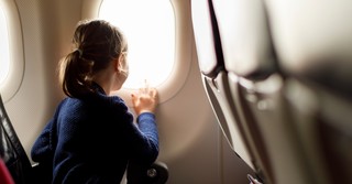 Little girl looking out an airplane window while travelling