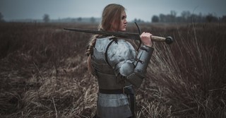 Woman wearing knight's armor, carrying a sword
