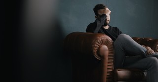 Sad man sitting on a couch in the dark