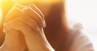 Close-up shot of a woman's hands folded in prayer