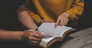 Two people reading the Bible together