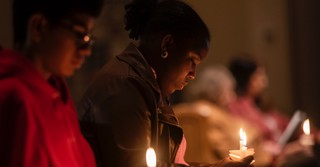 A woman holding a candle, praying at a vigil
