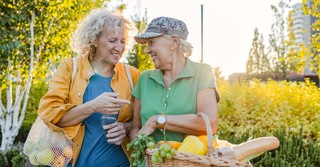 Older women planting a garden, talking and laughing together